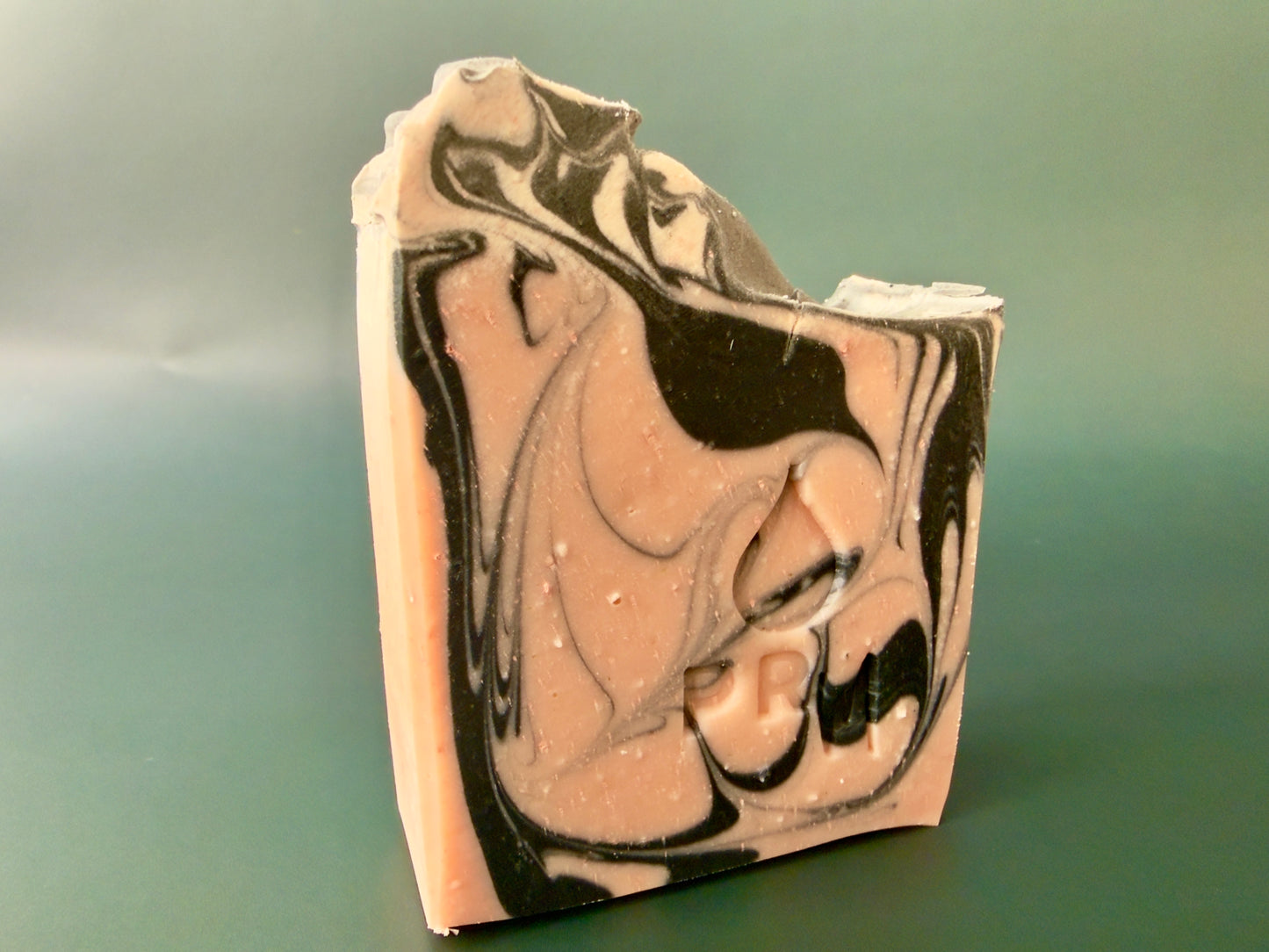 Loaf-cut soap bar with flowing charcoal and blush swirls, PRM stamp visible