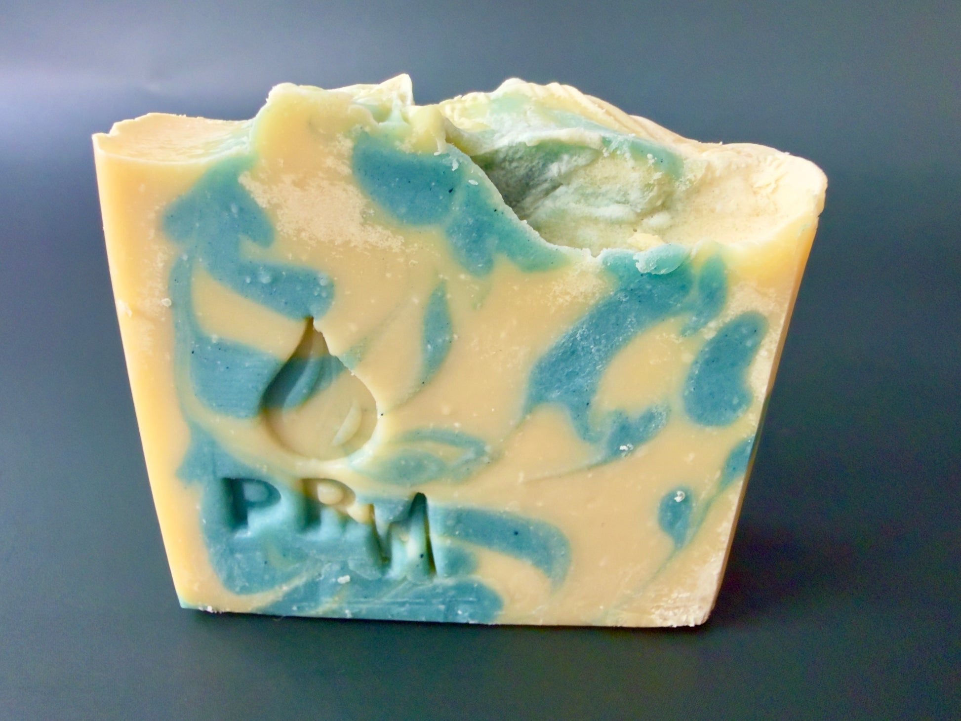 Loaf-cut soap bar with creamy base and blue-green swirl accents, PRM stamp visible
