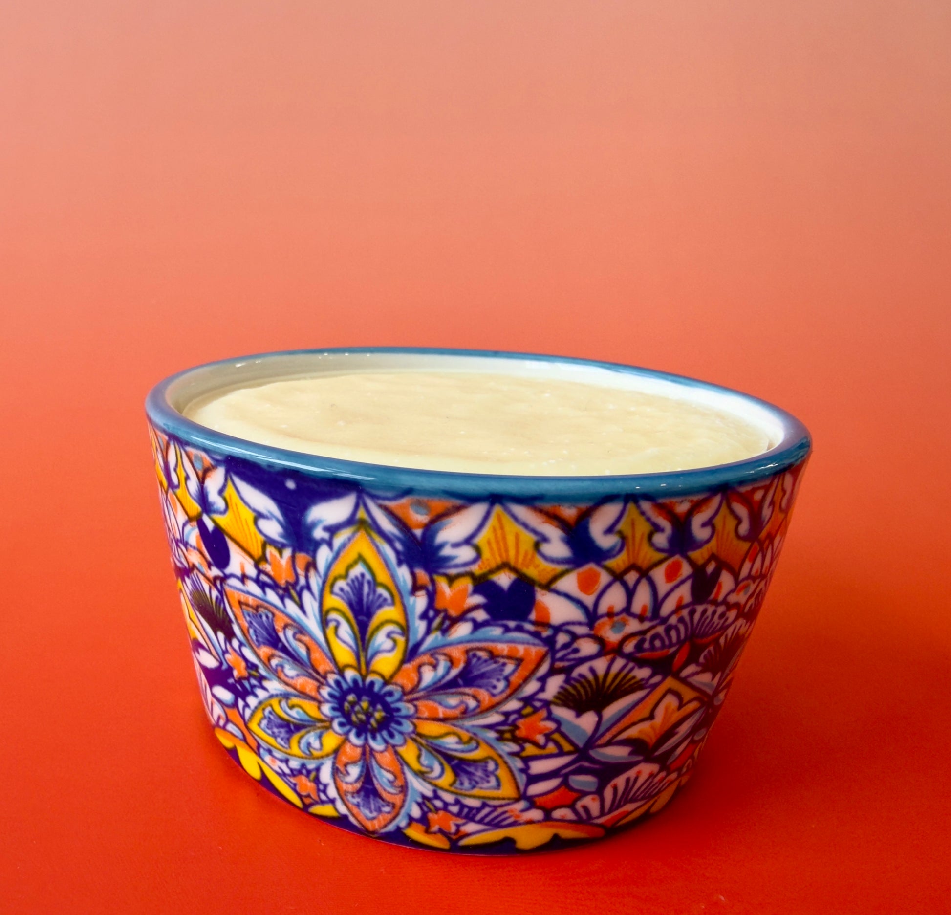 Citrus Burst solid dish soap poured into a patterned ceramic ramekin on an orange background