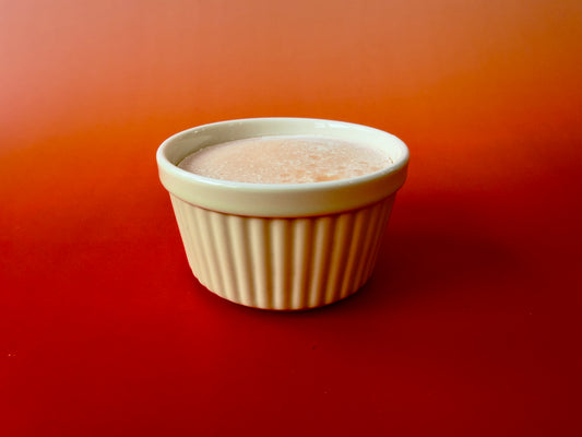 Solid dish soap poured into light green ceramic ramekin on warm orange background