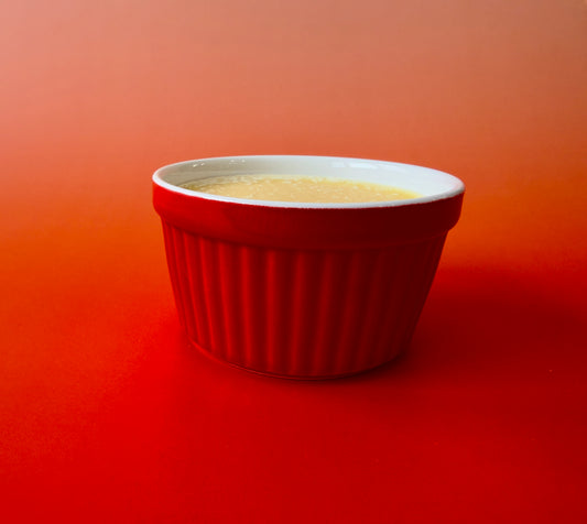 Solid dish soap poured into a red ceramic ramekin on a warm orange background