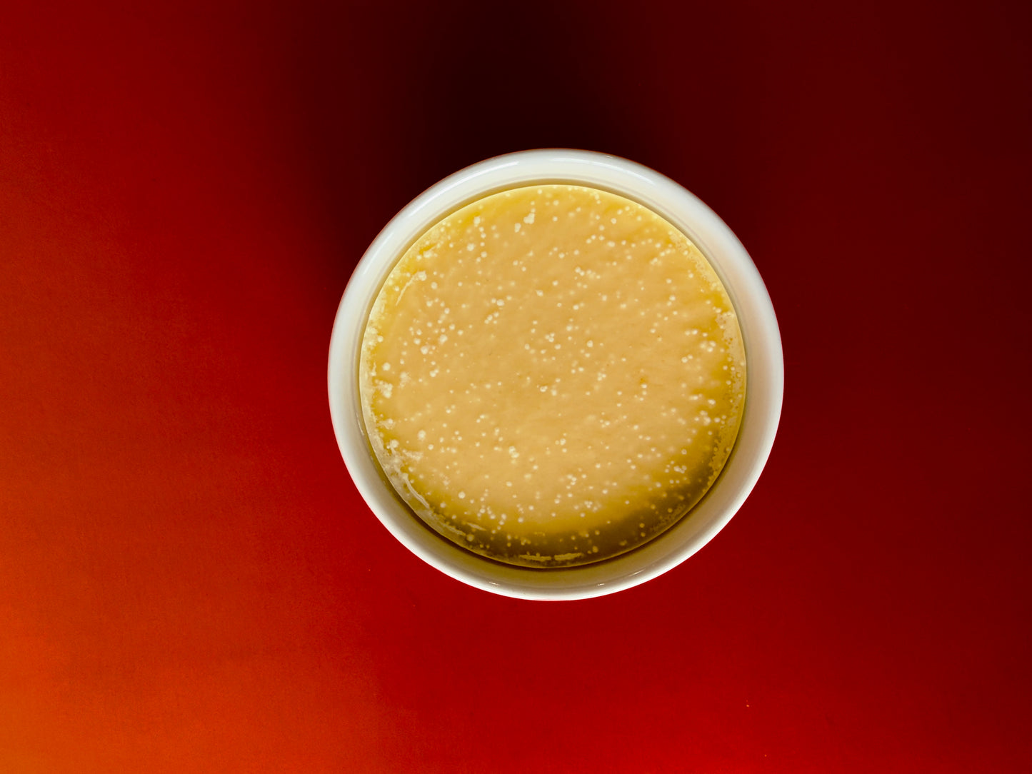 Top-down view of yellow-toned solid dish soap inside a ceramic ramekin