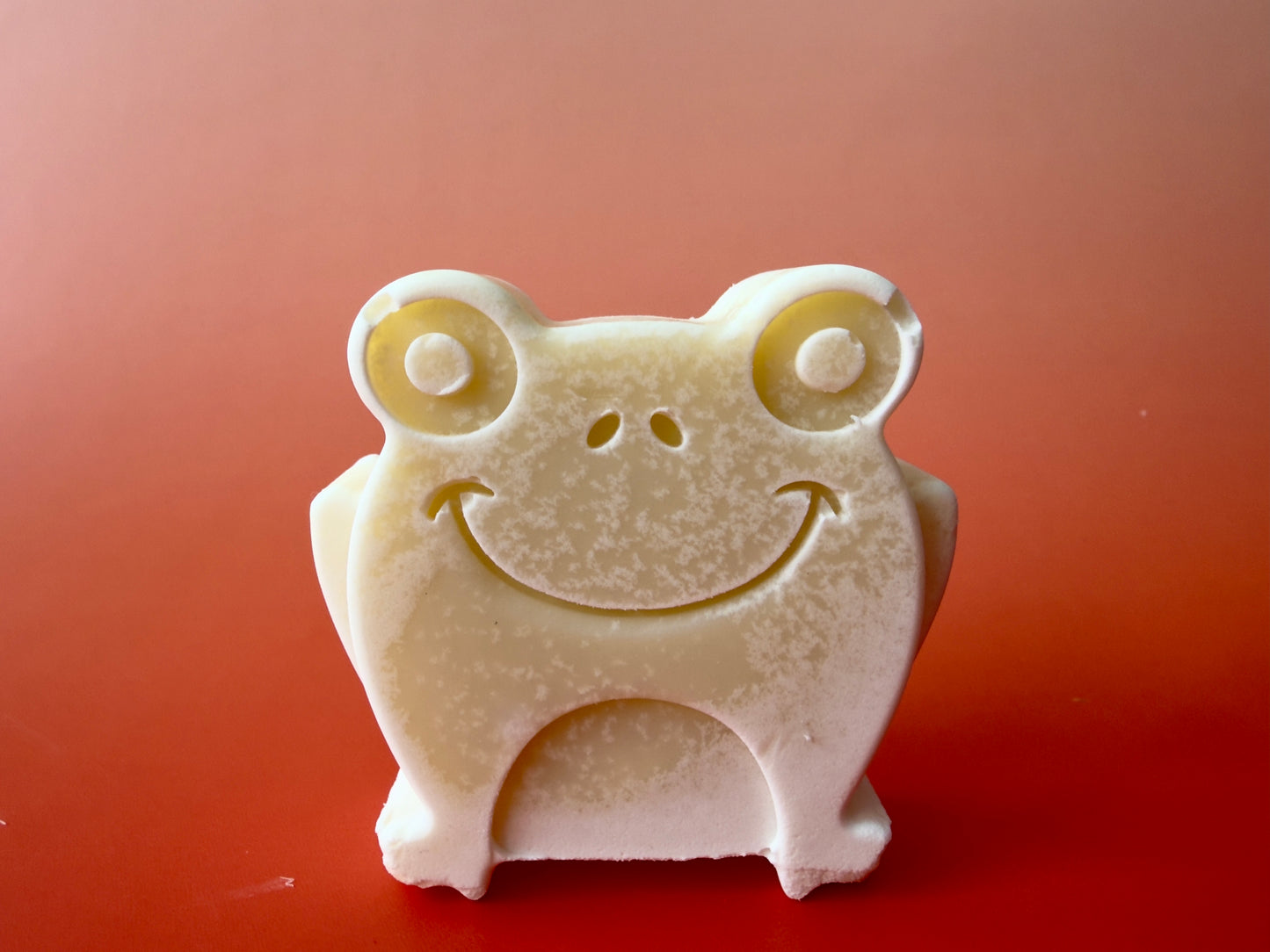 Gentle baby soap shaped like a smiling frog with rounded edges