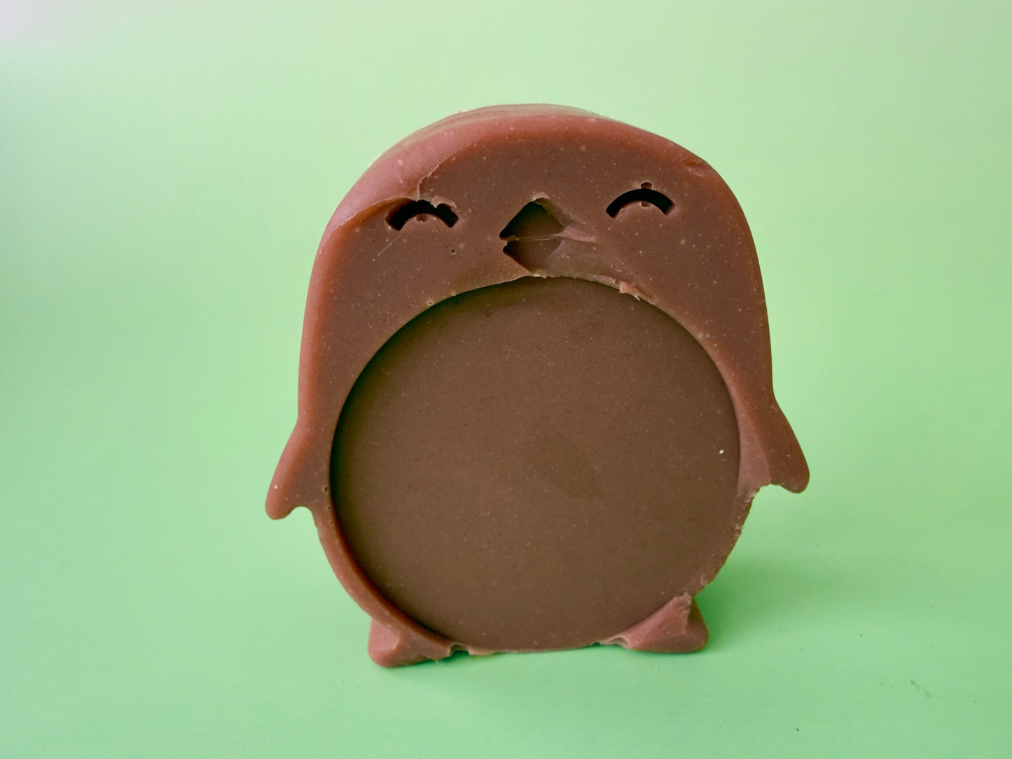 Shea butter baby soap shaped like a penguin with a rounded belly and clay tint