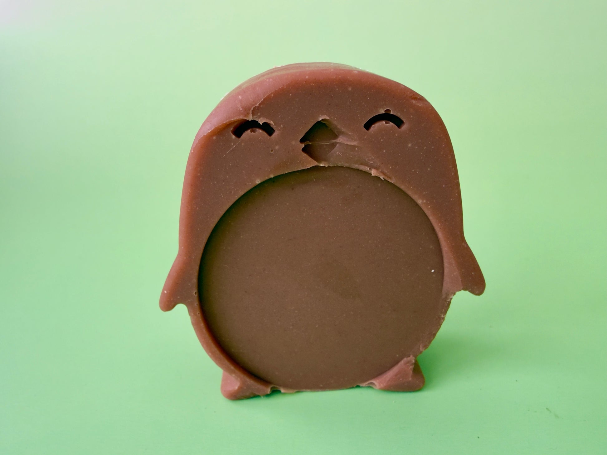 Shea butter baby soap shaped like a penguin with a rounded belly and clay tint