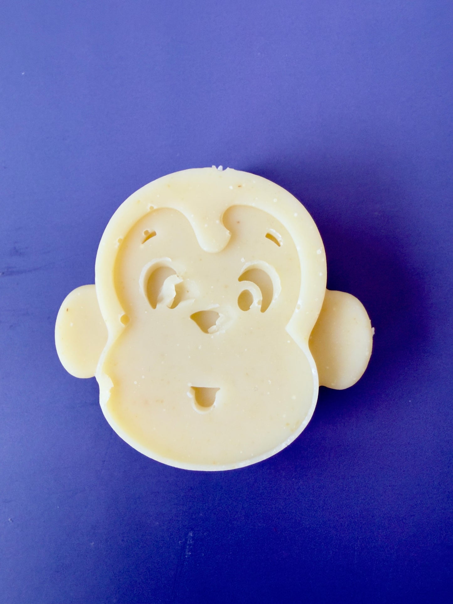 Shea butter baby soap molded as a monkey face on a cool blue background
