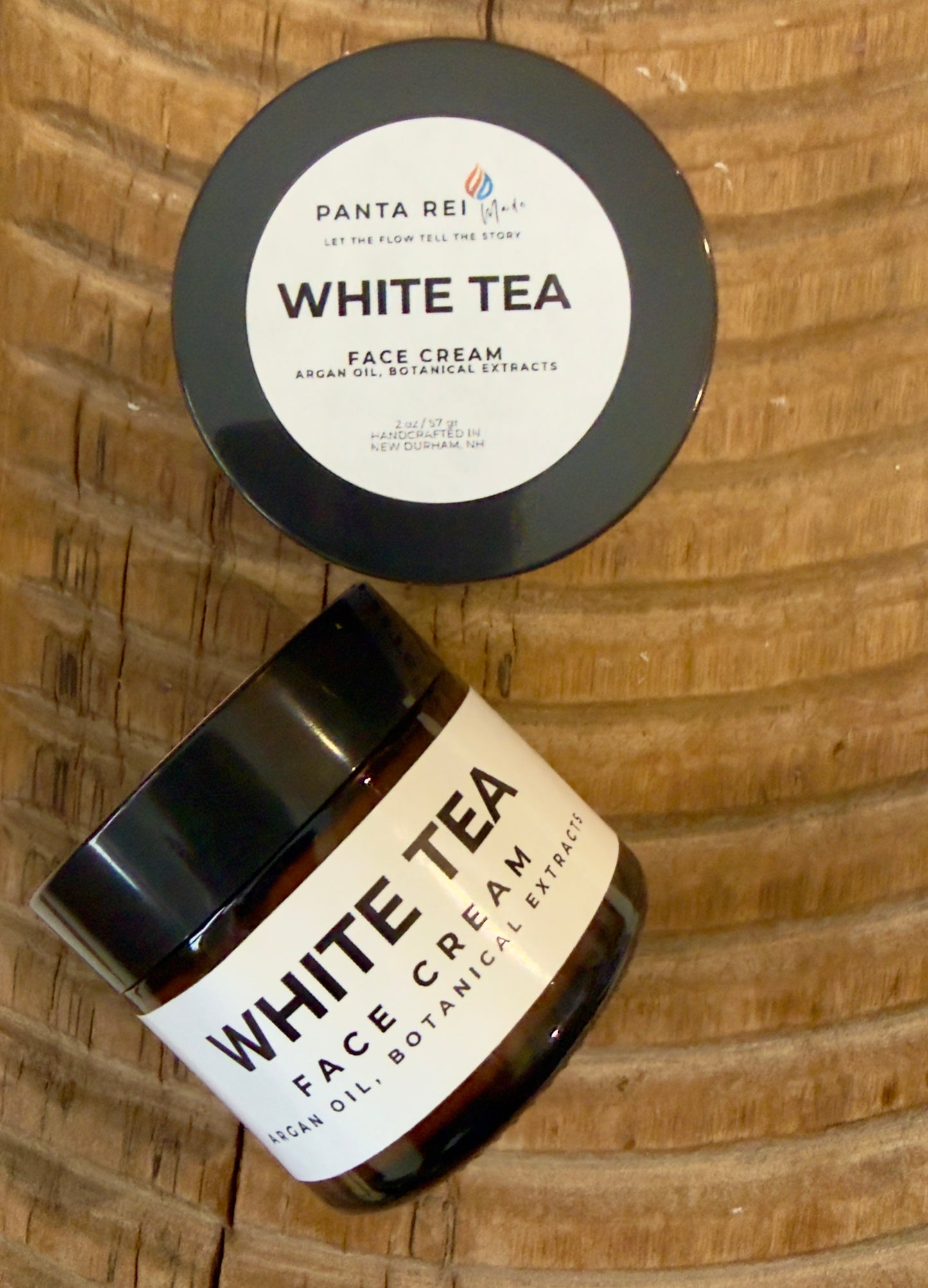 Face cream in amber glass jar with minimalist Panta Rei Made label on wood surface (white tea)