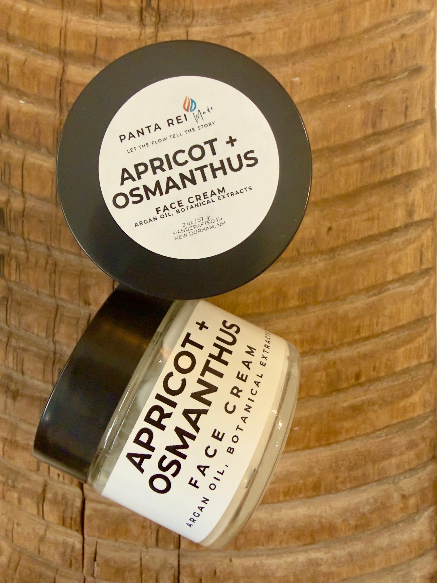 Face cream in amber glass jar with minimalist Panta Rei Made label on wood surface (apricot + osmanthus)