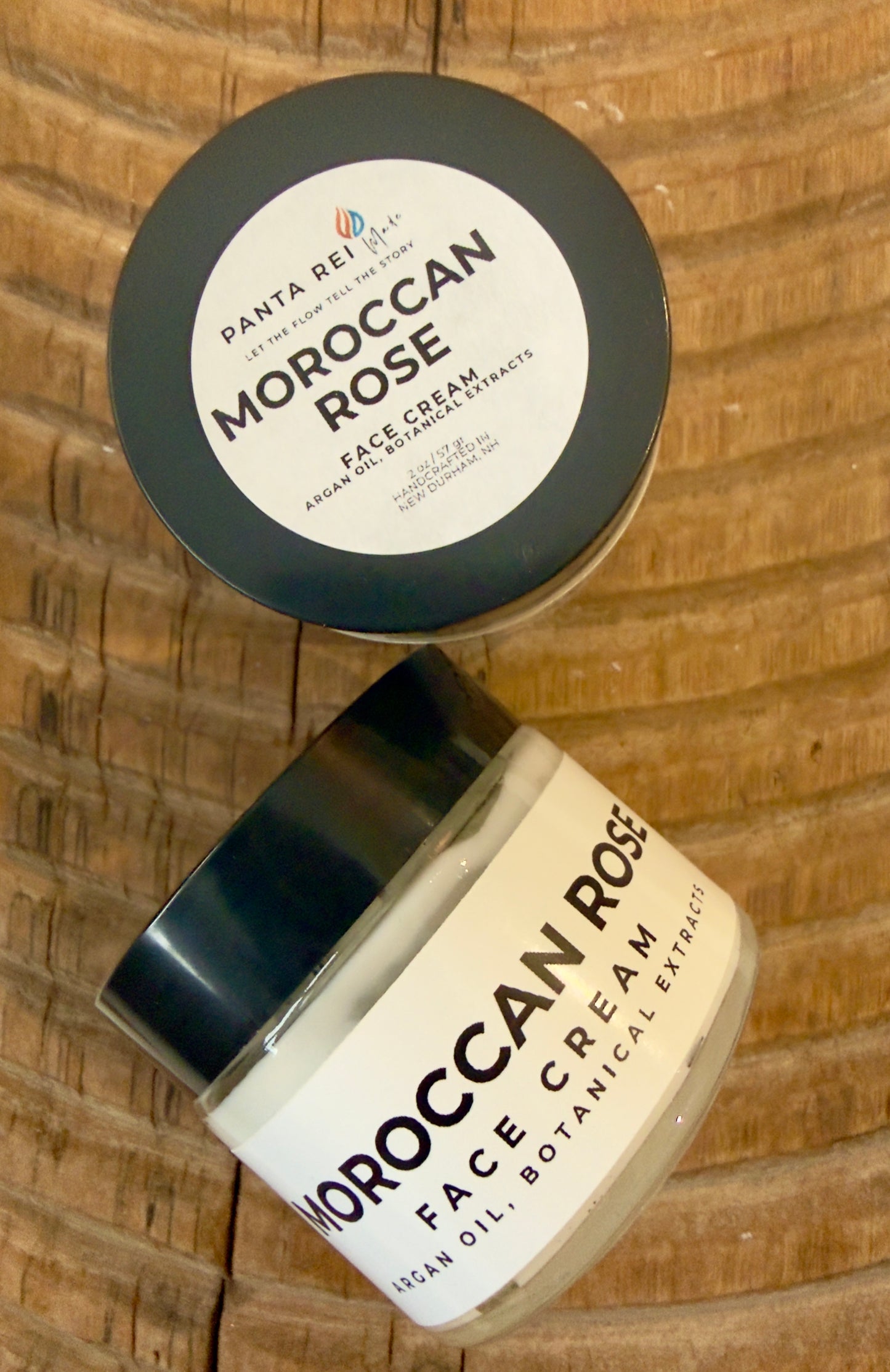 Face cream in amber glass jar with minimalist Panta Rei Made label on wood surface (Moroccan rose)