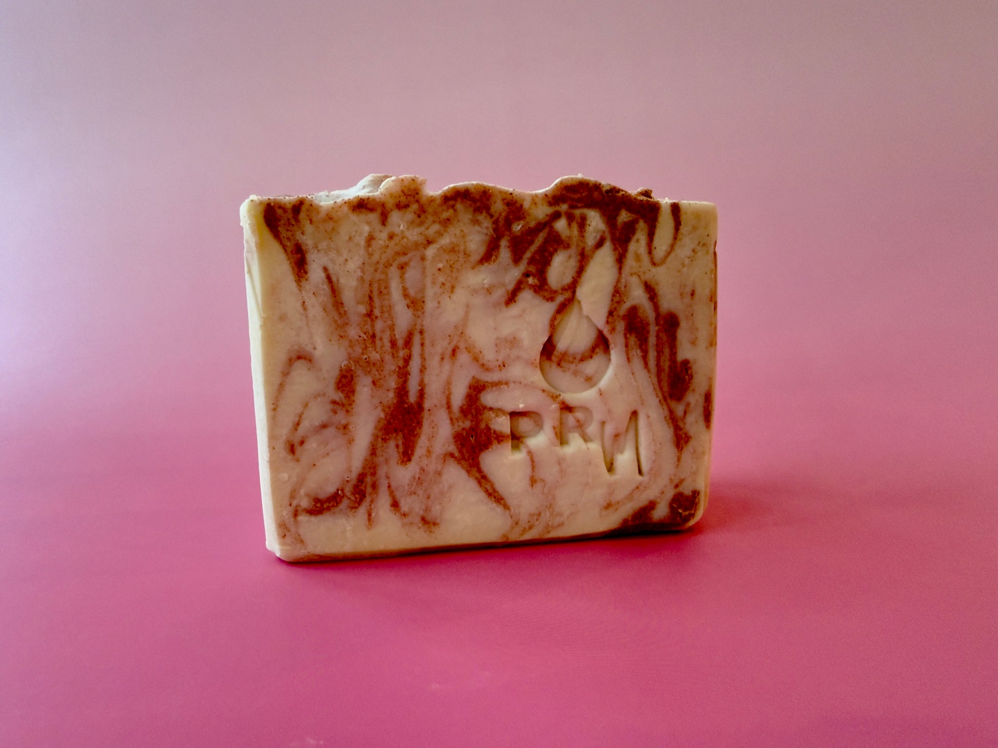 Sweet Bergamot small batch aloe soap with cream and copper swirl on a pink background.