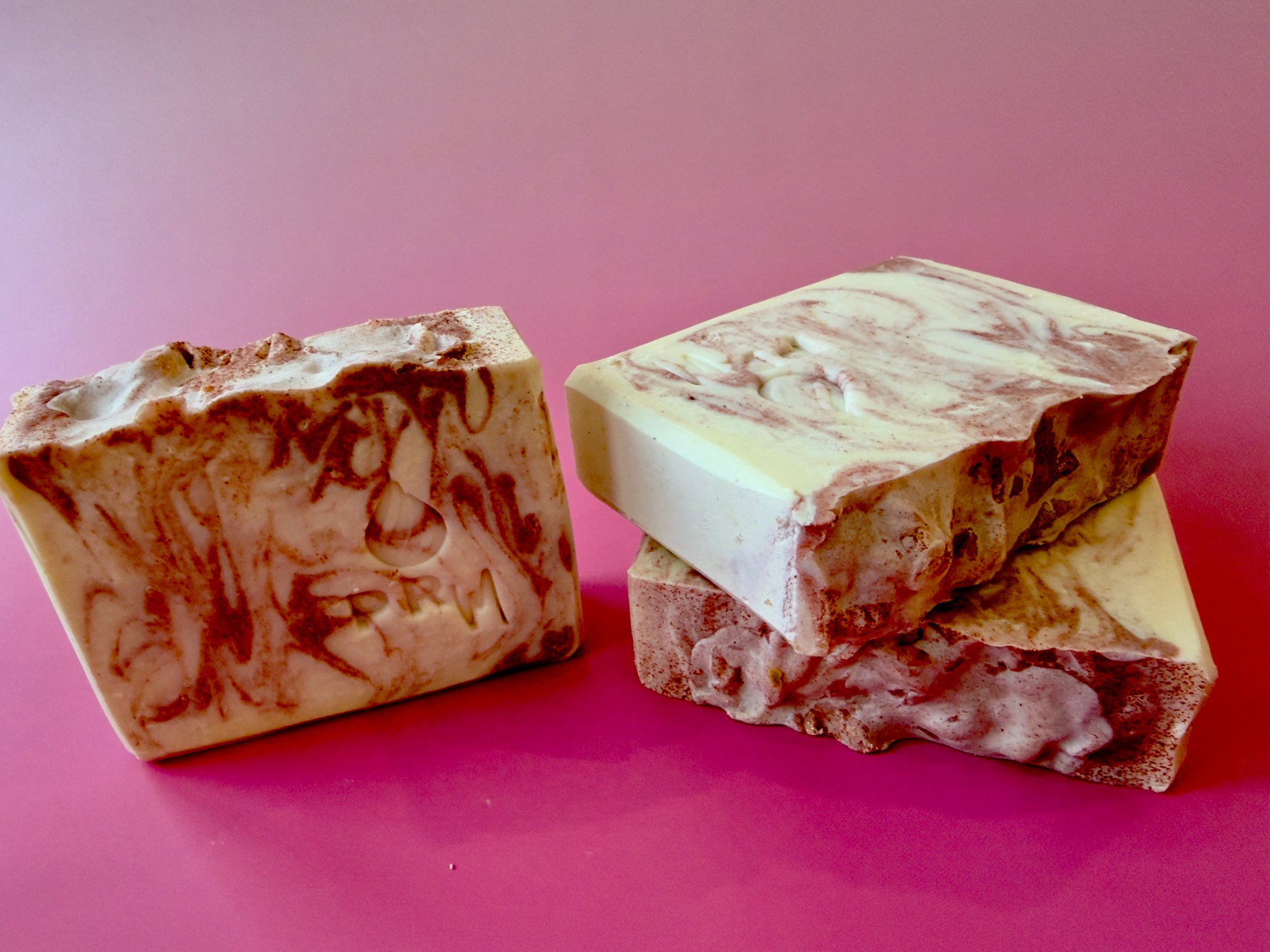 Sweet Bergamot small batch aloe soap with cream and copper swirl on a pink background.