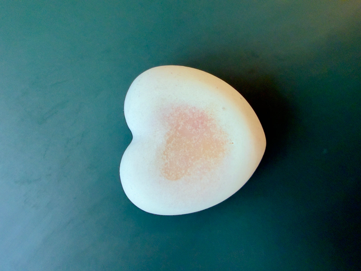 Citrus + Musk goat milk heart soap with a soft pink shimmer accent on a dark green background.