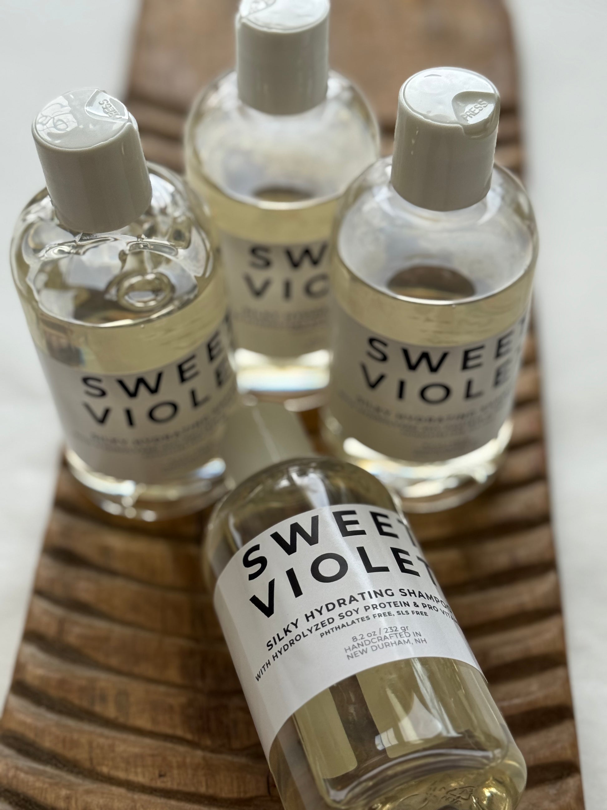 Panta Rei Made Sweet Violet shampoo in clear bottles with white flip-top caps.