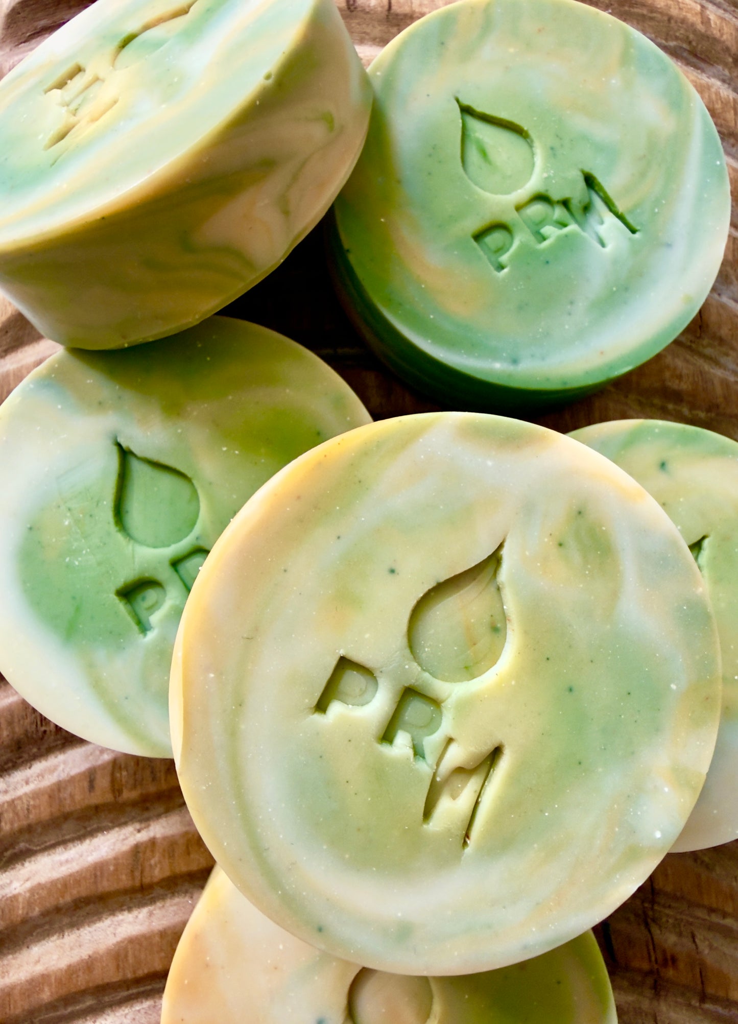 Yellow and Green soap bars with 'PRM' branding on a wooden surface