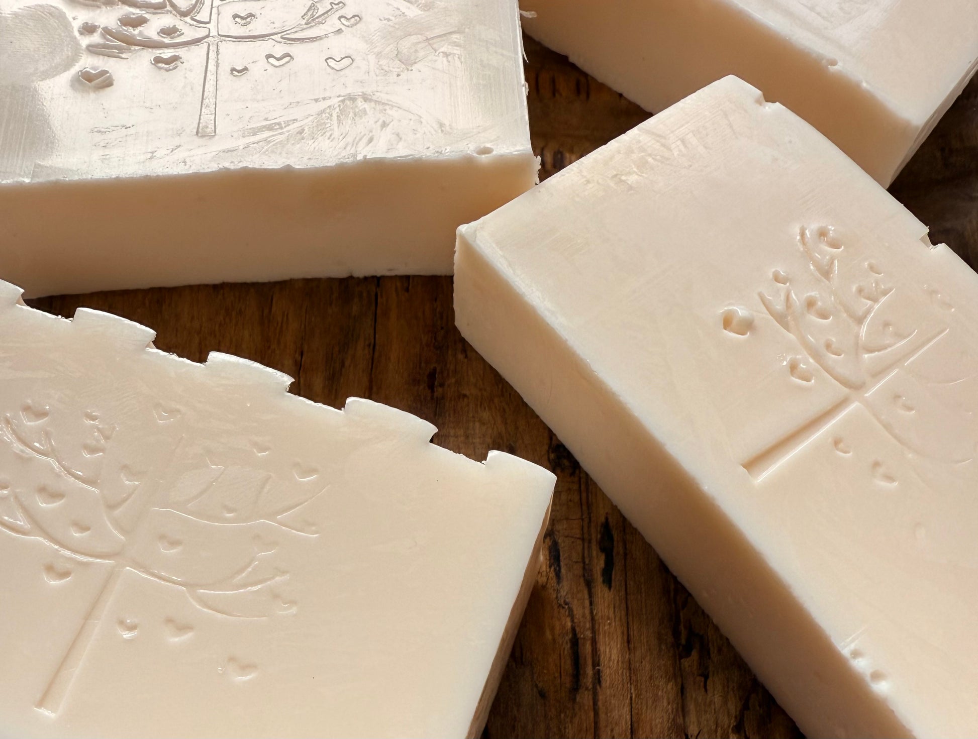 White soap bars with embossed designs on a wooden surface
