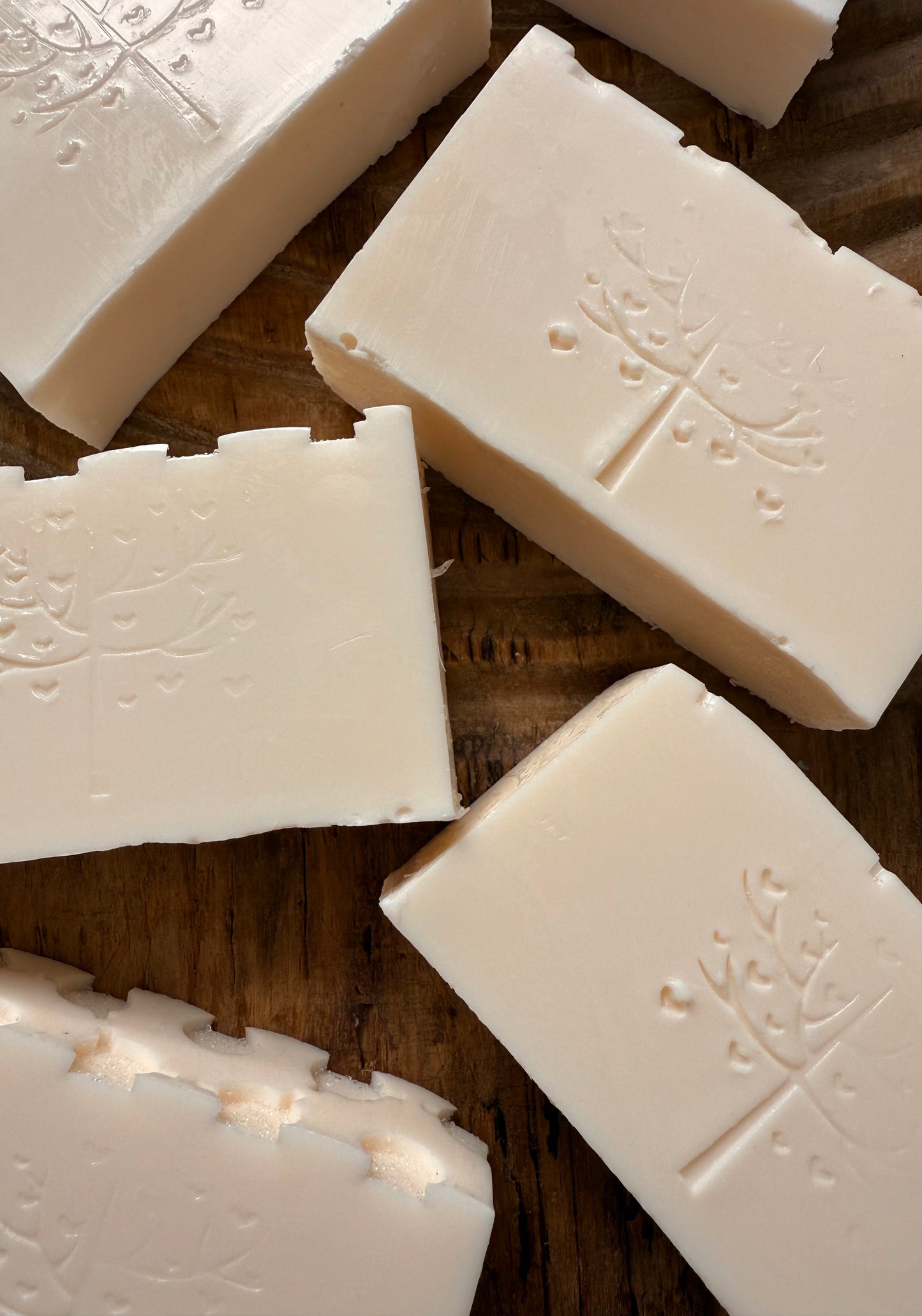 White soap bars with embossed designs on a wooden surface