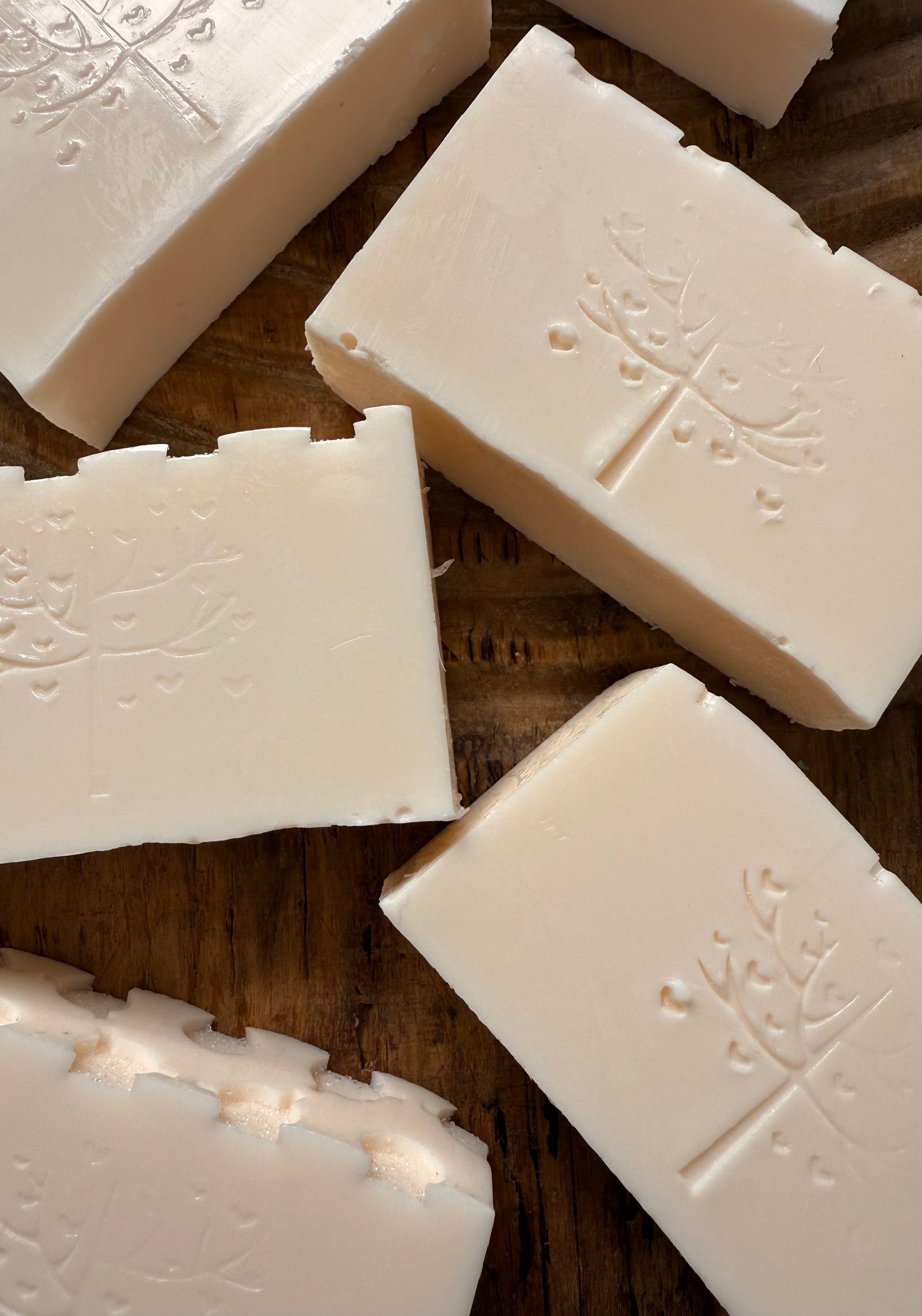 White soap bars with embossed designs on a wooden surface