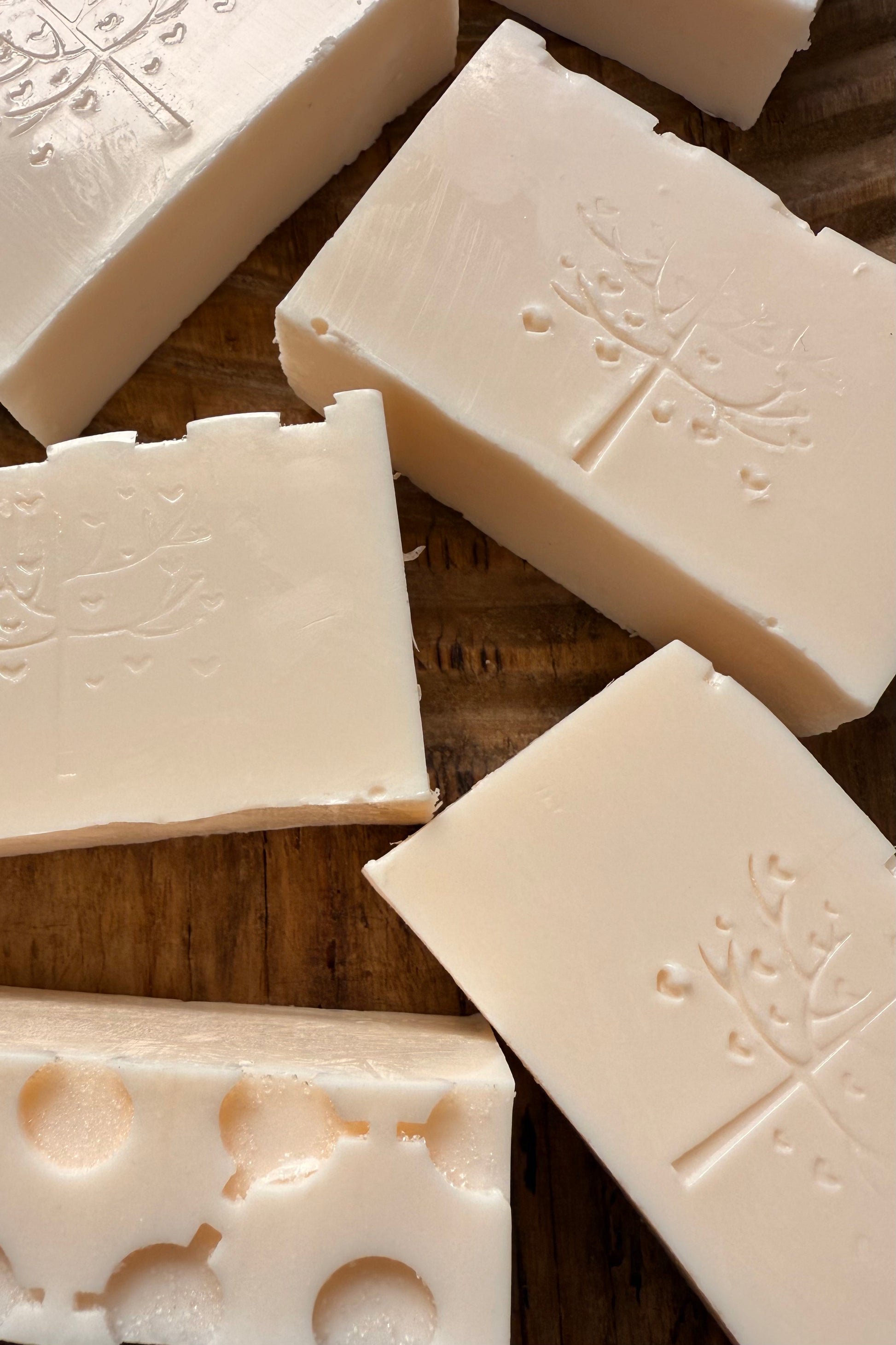 White soap bars with embossed designs on a wooden surface
