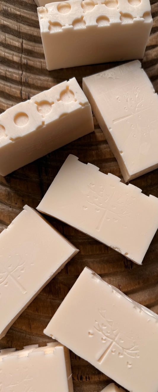 Multiple bars of white soap with a textured surface on a wooden background