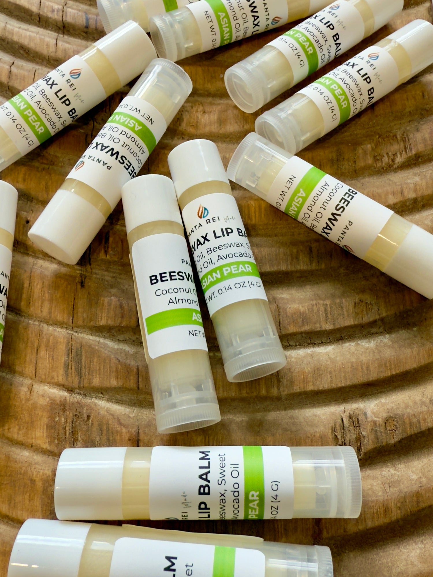 Asian Pear lip balm tubes arranged on carved wooden tray with green labels.